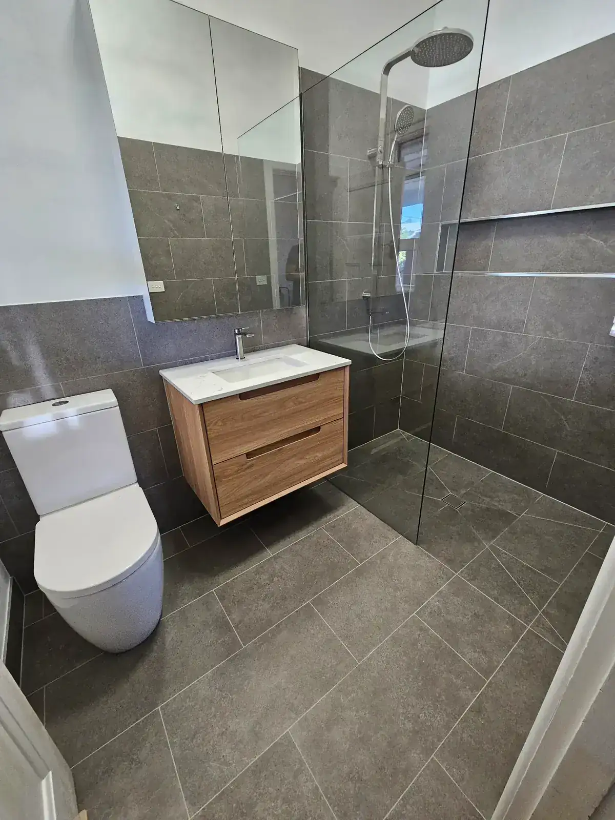 Newport bathroom rebuilt with grey stone and timber vanity