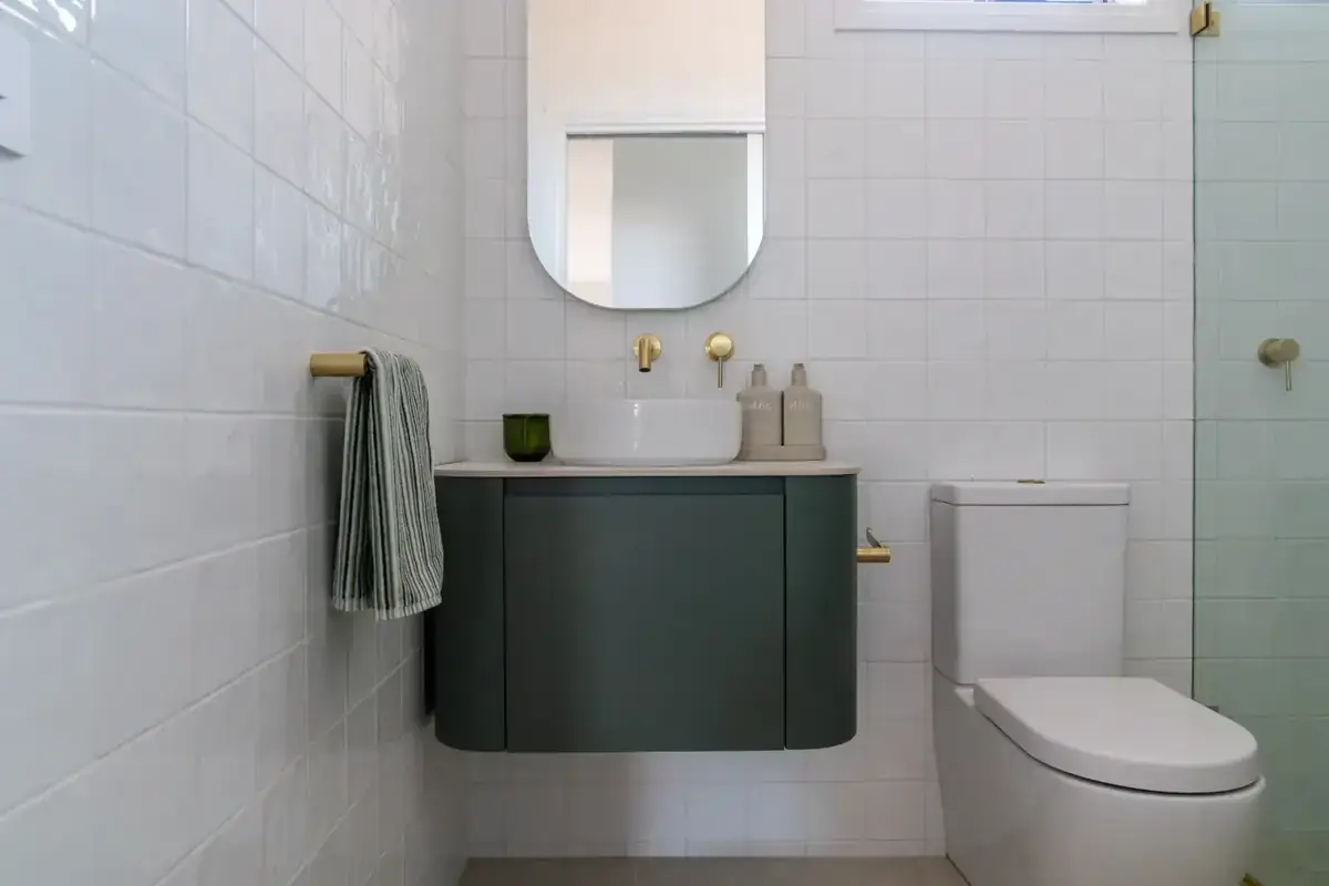Editorial bathroom with curved green vanity and brass tapware